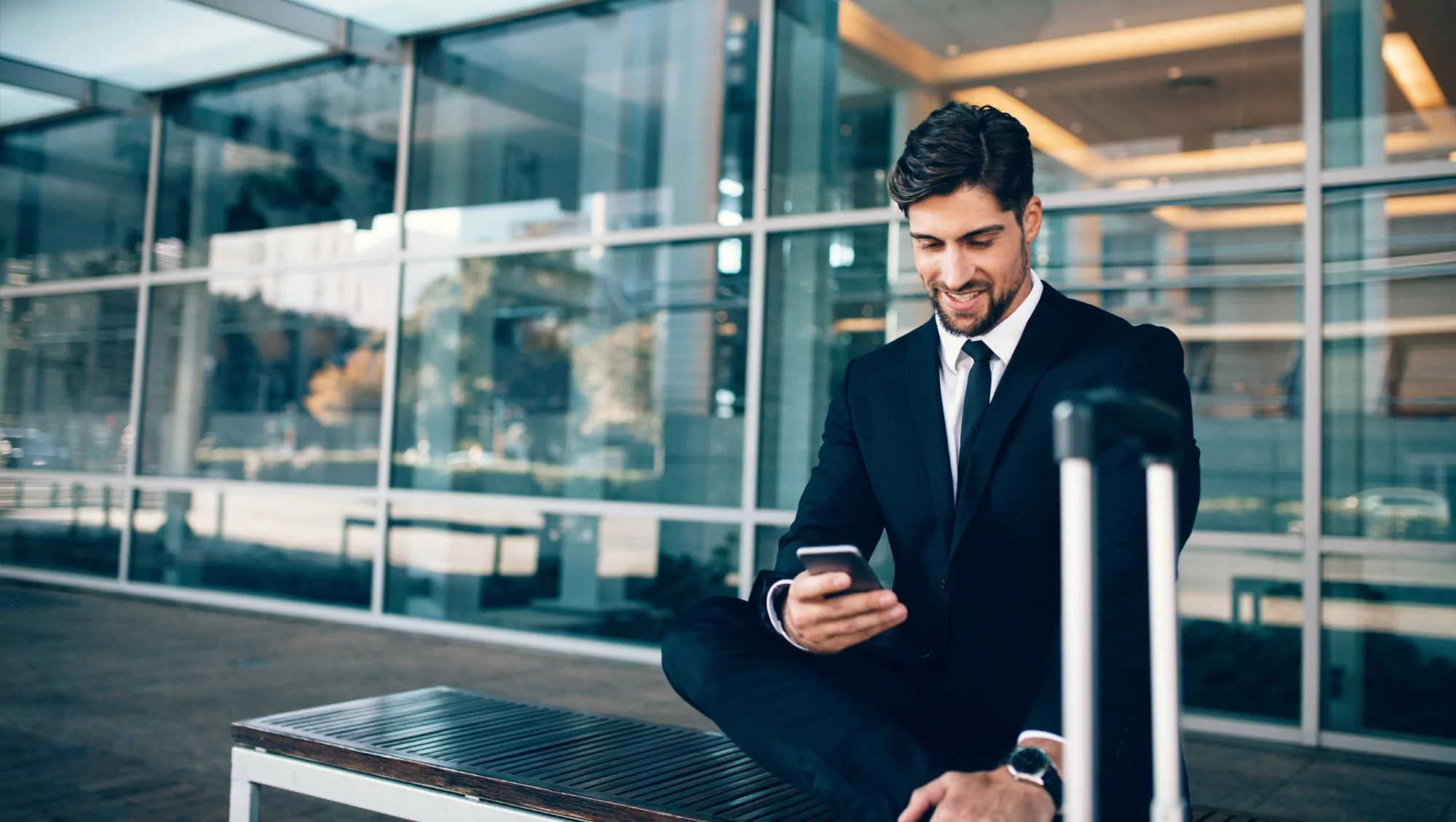 Person dressed in suit looks at phone while seated at airport